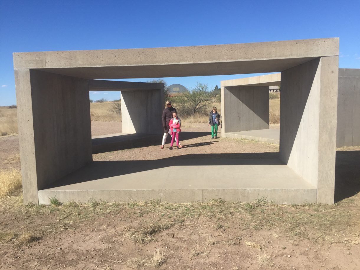 Woman and two children in front of concrete structures