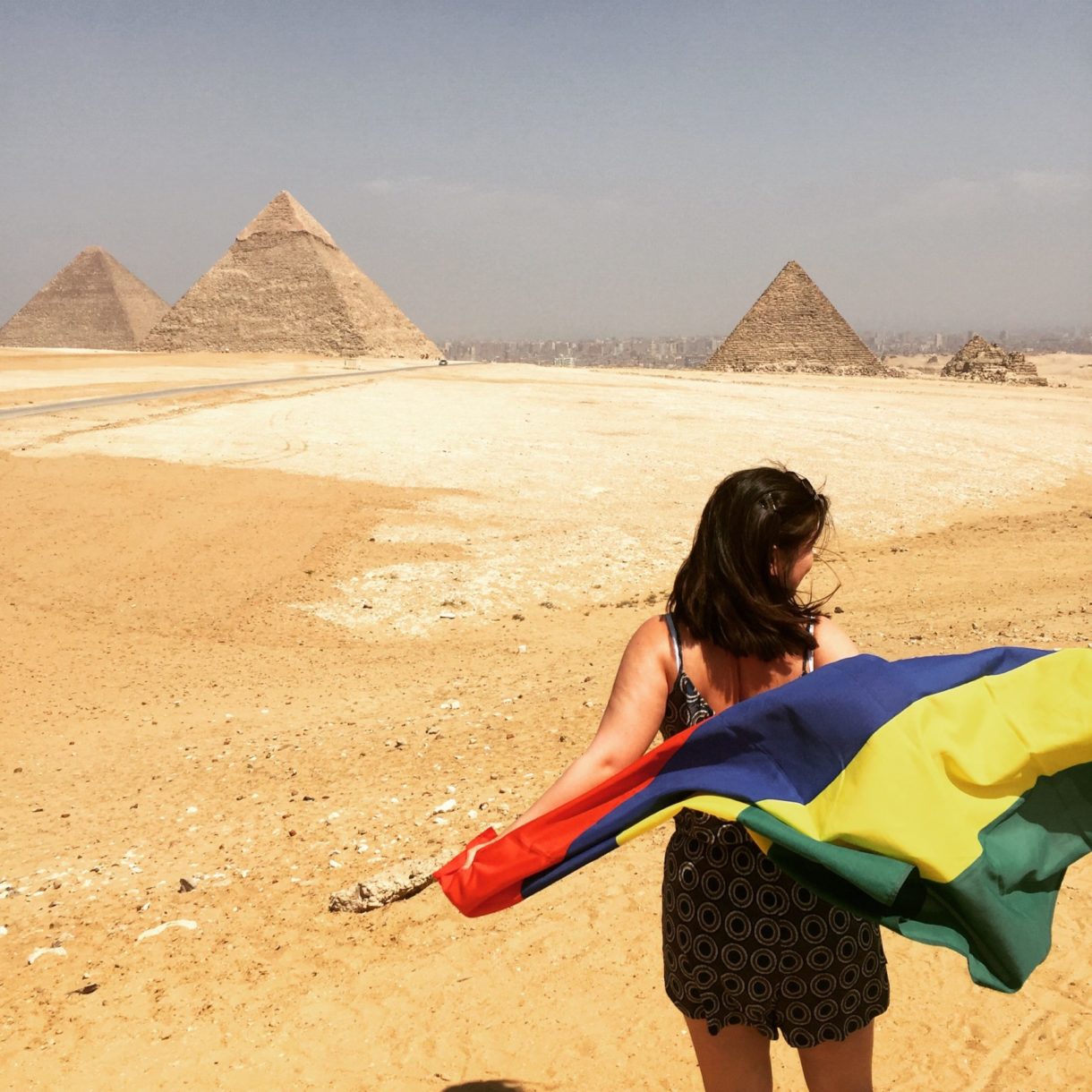woman holding flag in front of pyramids